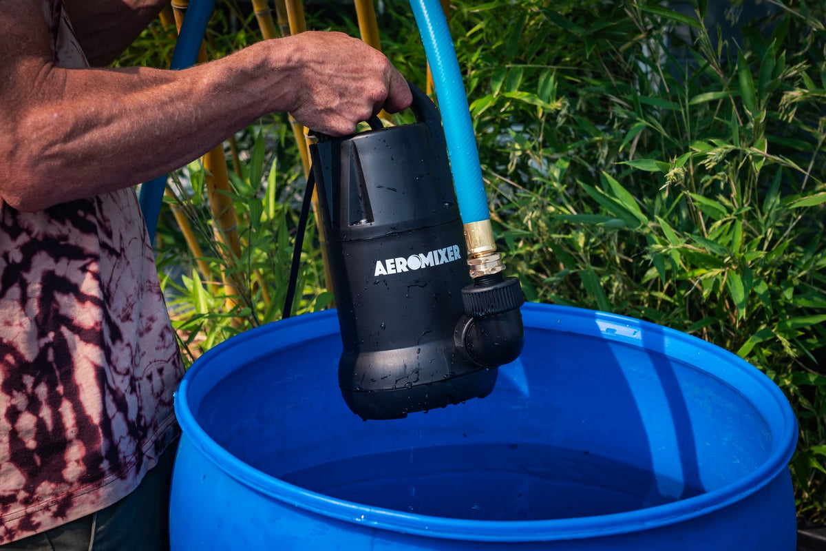 Aeromixer lowered by hand into a blue 55-gallon barrel