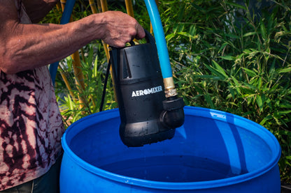 Aeromixer lowered by hand into a blue 55-gallon barrel