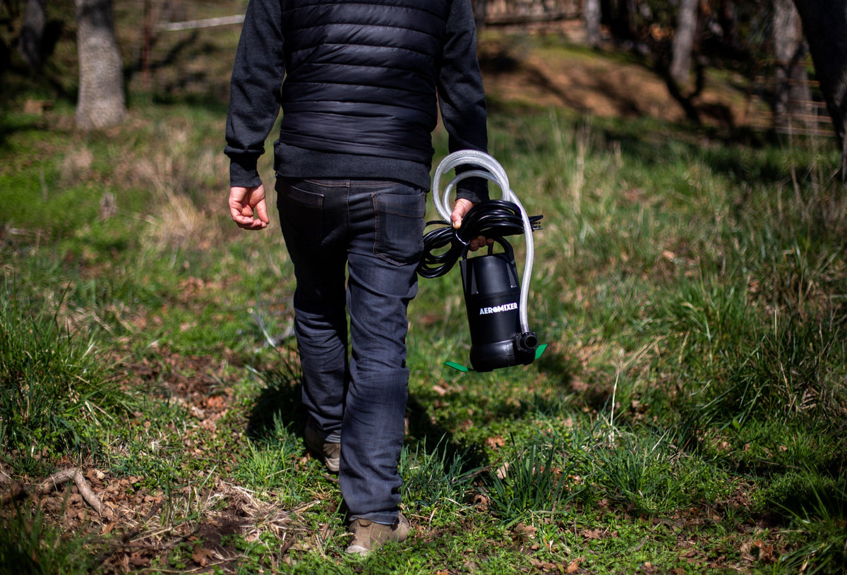 Carrying the Aeromixer and its air hose across a field