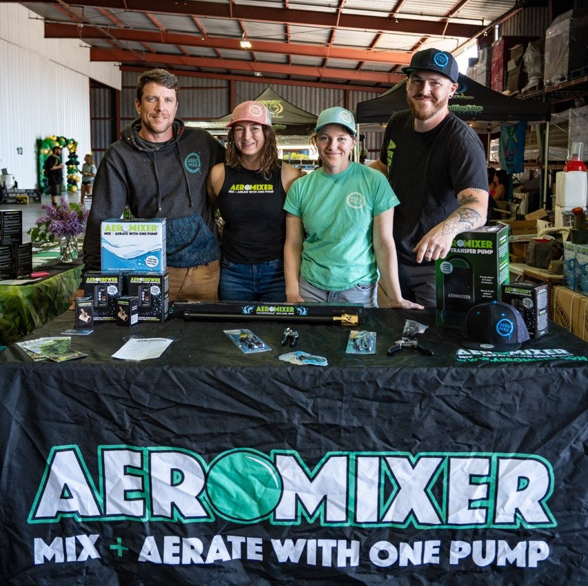 The Aeromixer team behind the booth table at an event, products laid out
